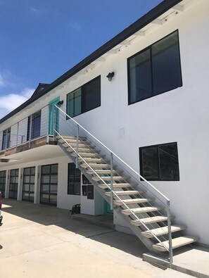 Un edificio con una escalera que lleva a un balcón, grandes ventanales y un diseño limpio y moderno.