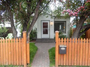 Une maison avec un porche à l’avant, une boîte aux lettres et une clôture en bois.