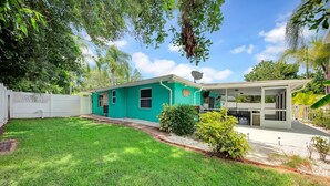 A two-story house with a green exterior, a covered patio, and a well-maintained lawn. - Tana’s Siesta Getaway - Heated Private Pool (Sarasota)