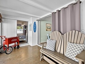 Une chambre avec un lit, une chaise, un réfrigérateur pour les canettes de Coca-Cola et une vue sur la plage, visible à travers une porte vitrée.