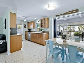 Une cuisine moderne avec des meubles en bois, un lave-vaisselle encastré et un coin repas avec des chaises bleues.