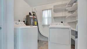 A laundry room with two white washing machines, a dryer, and a water heater. - Tana’s Siesta Getaway - Heated Private Pool (Sarasota)