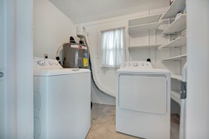 A laundry room with two white washing machines, a dryer, and a water heater. - Tana’s Siesta Getaway - Heated Private Pool (Sarasota)