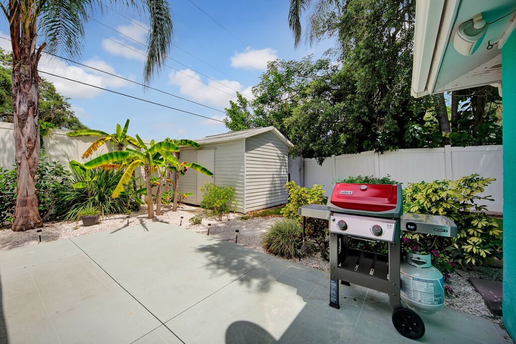 Ein Garten mit Grill, Gartenhaus und verschiedenen Pflanzen.