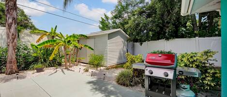 Ein Garten mit Grill, Gartenhaus und verschiedenen Pflanzen.