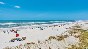 Una playa con arena, sombrillas y sillas de playa.