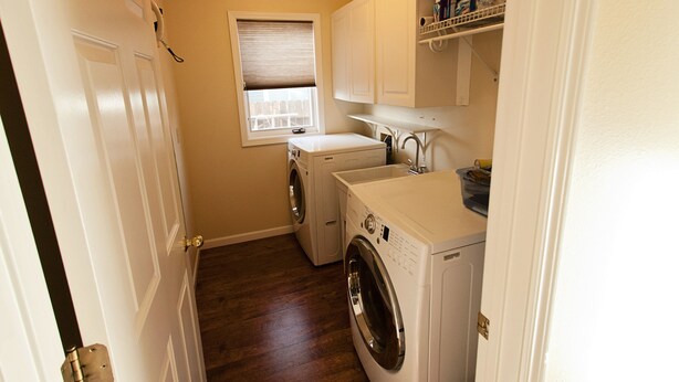 A laundry room with a washing machine, dryer, and sink.