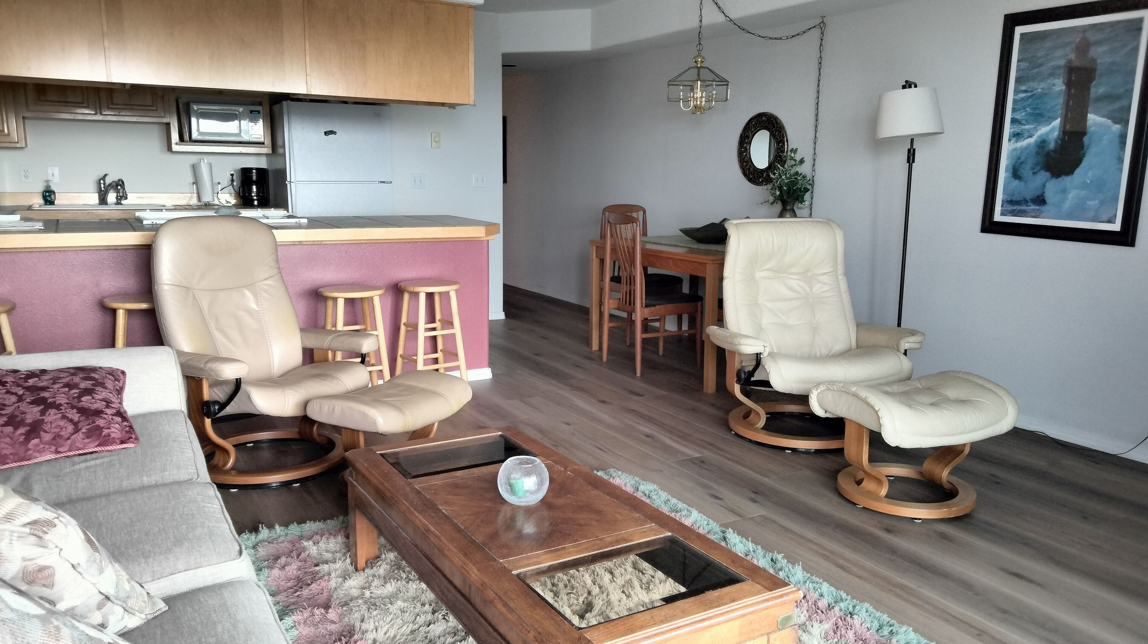 Un salon moderne comprenant un canapé, deux fauteuils, une table basse et un coin repas avec une table et des chaises.