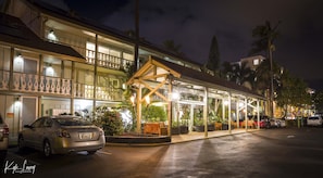 Ein Hotel mit überdachtem Außenbereich, mehreren Etagen und einem geparkten Auto vor der Tür.