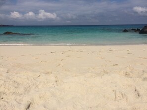 Ein Strand mit Fußabdrücken im Sand und ruhiger See.