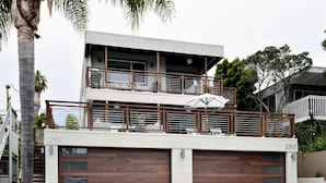 A modern two-story house with a balcony, garage doors, and a number '2311'.