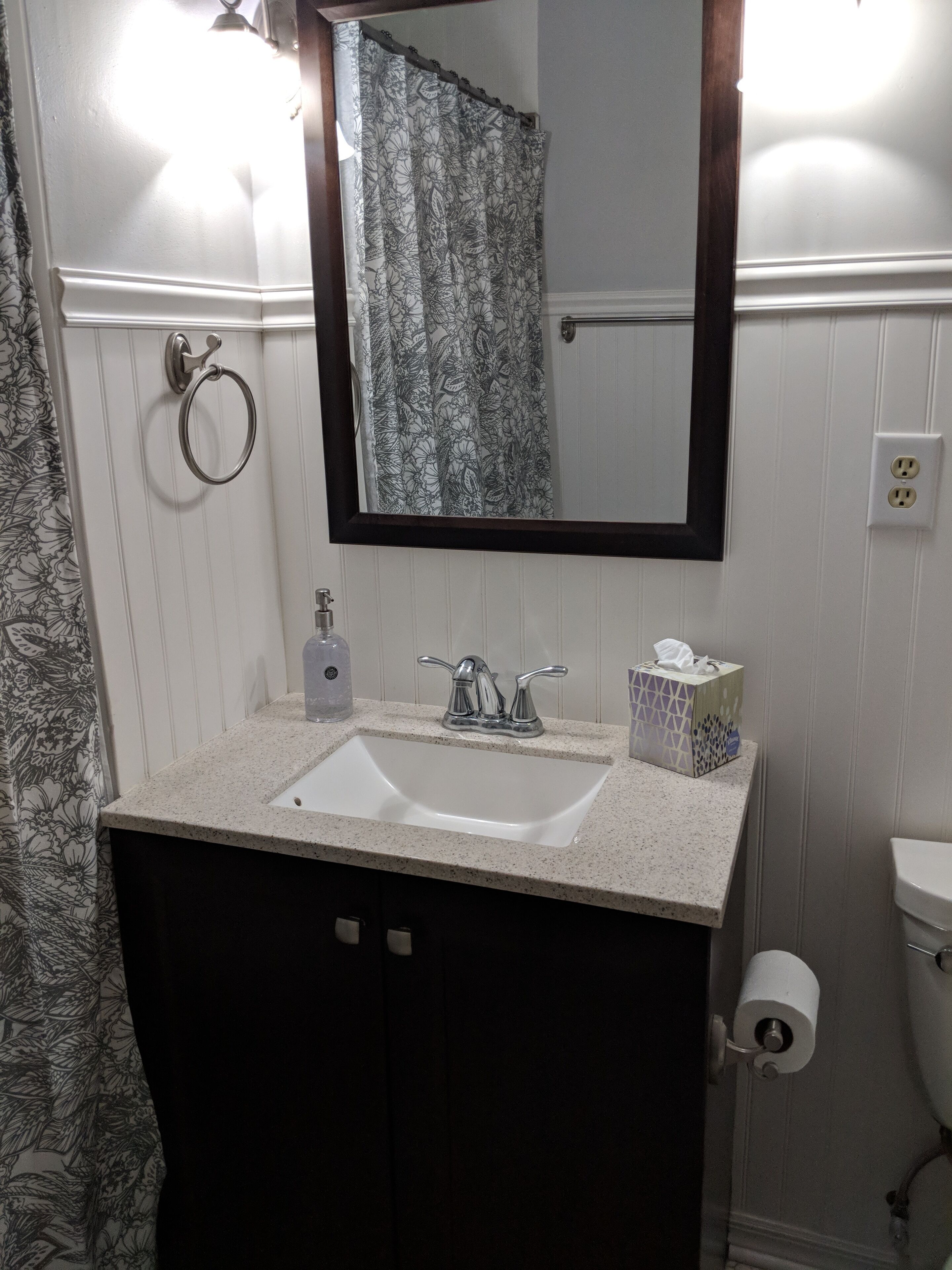 A bathroom with a white sink, a mirror, a toilet, and a shower curtain.
