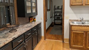 Una cocina con armarios de madera oscura, encimera de granito y puerta de madera que da a un pasillo.