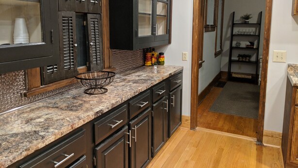 Cocina con armarios de madera oscura, encimera de granito y piso de madera.
