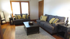 A living room with a grey sofa, a coffee table, and a wooden floor.