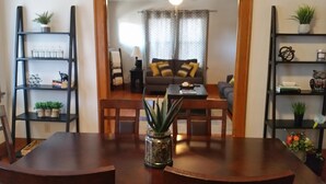 Un comedor con una mesa de madera, sillas y una planta en maceta en el centro.