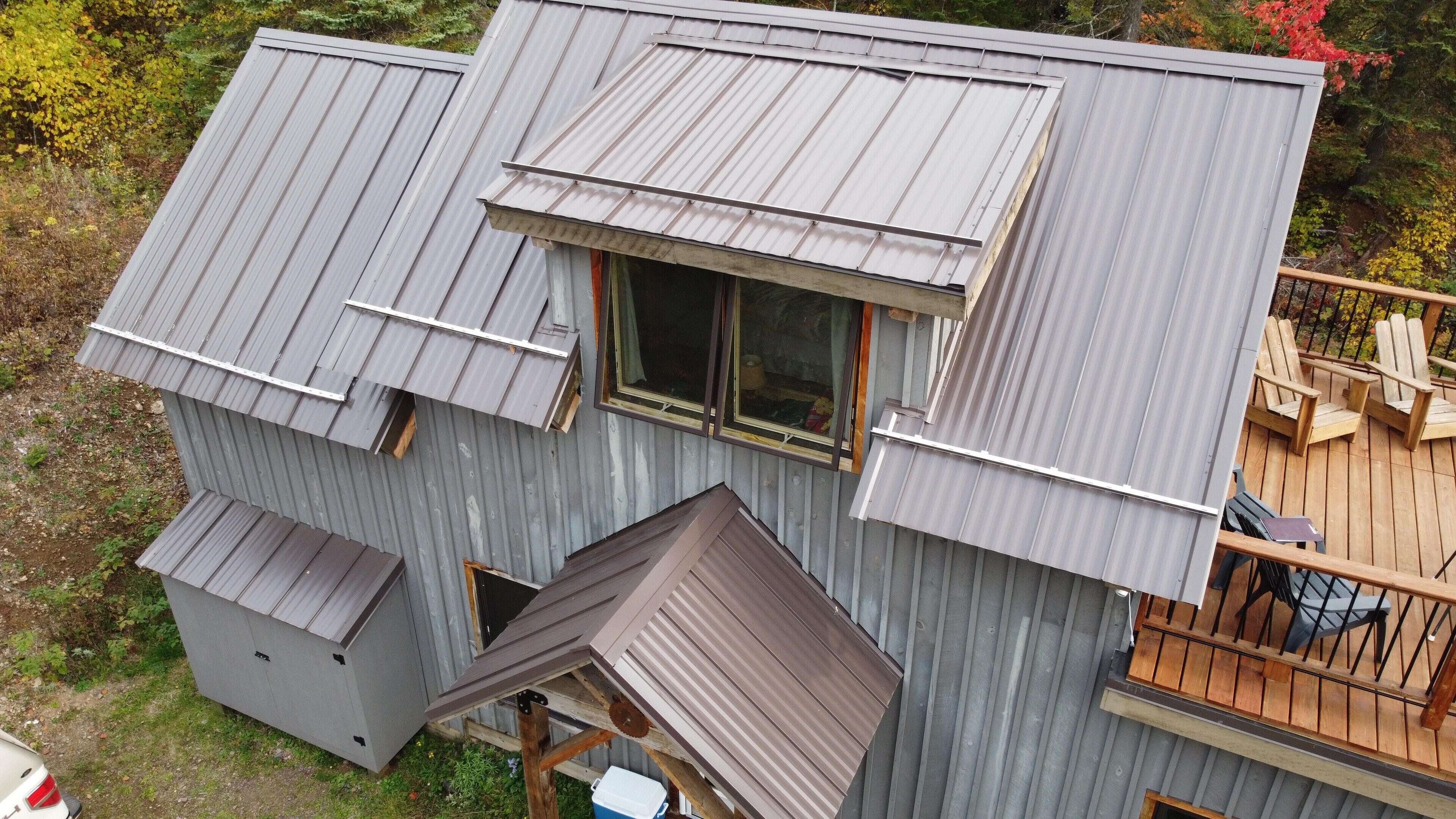 A metal-roofed cabin with a deck and a small window.