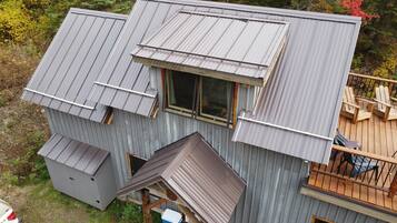 A metal-roofed cabin with a deck and a small window.