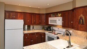 A kitchen with wooden cabinets, a white refrigerator, a microwave, a stove, and a sink. - Culp House: Ideal Location, Historic Gettysburg! Can Rent with the Cricket House (Gettysburg)