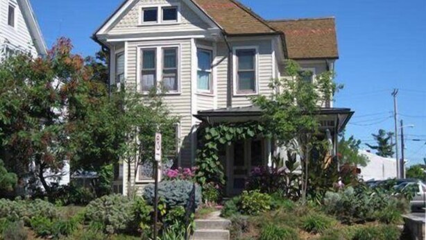A two-story house with a front porch, surrounded by lush greenery and a clear blue sky. - Culp House: Ideal Location, Historic Gettysburg! Can Rent with the Cricket House (Gettysburg)