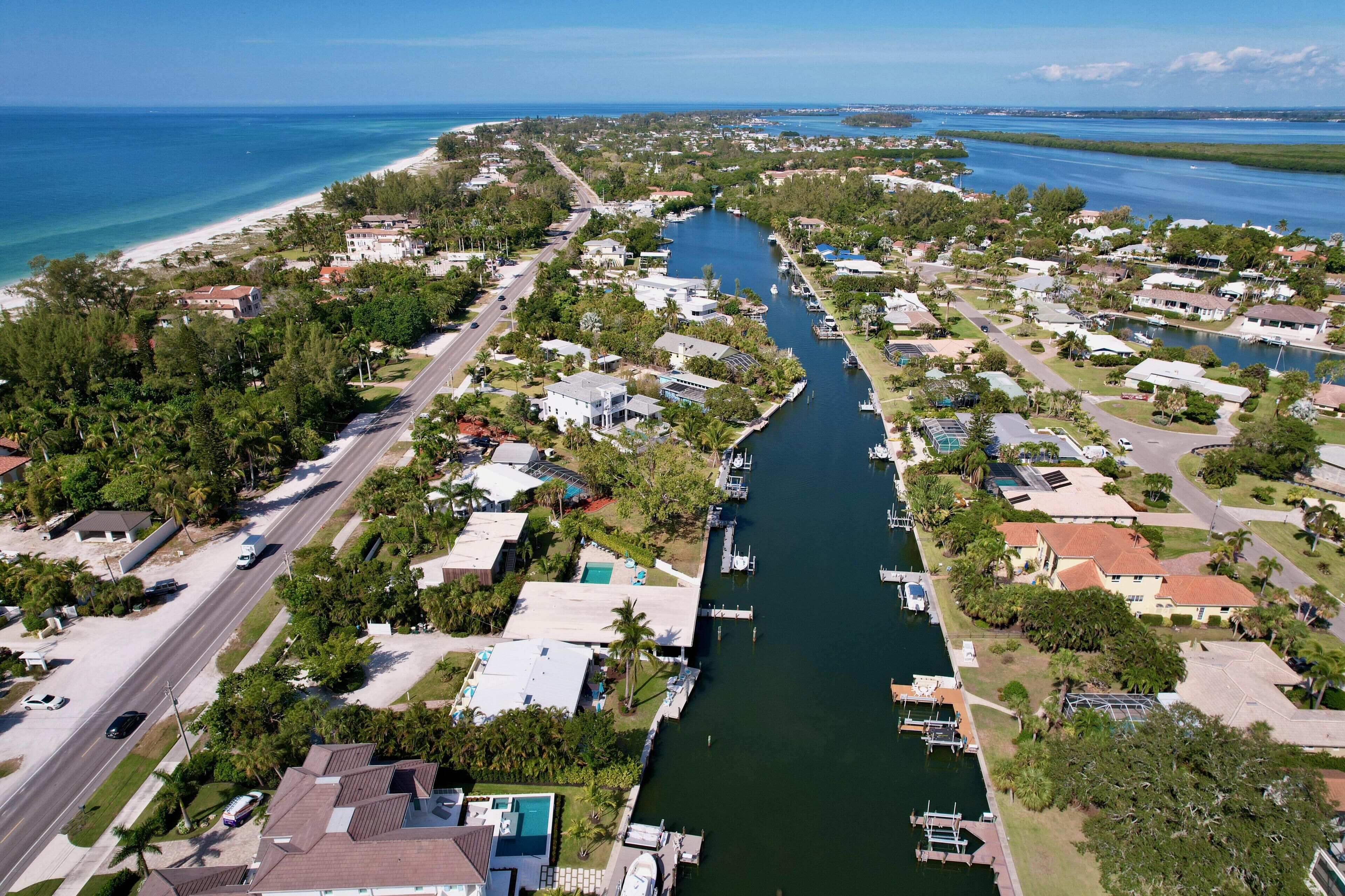 An aerial view of a coastal residential area with houses, a marina, and a beach.