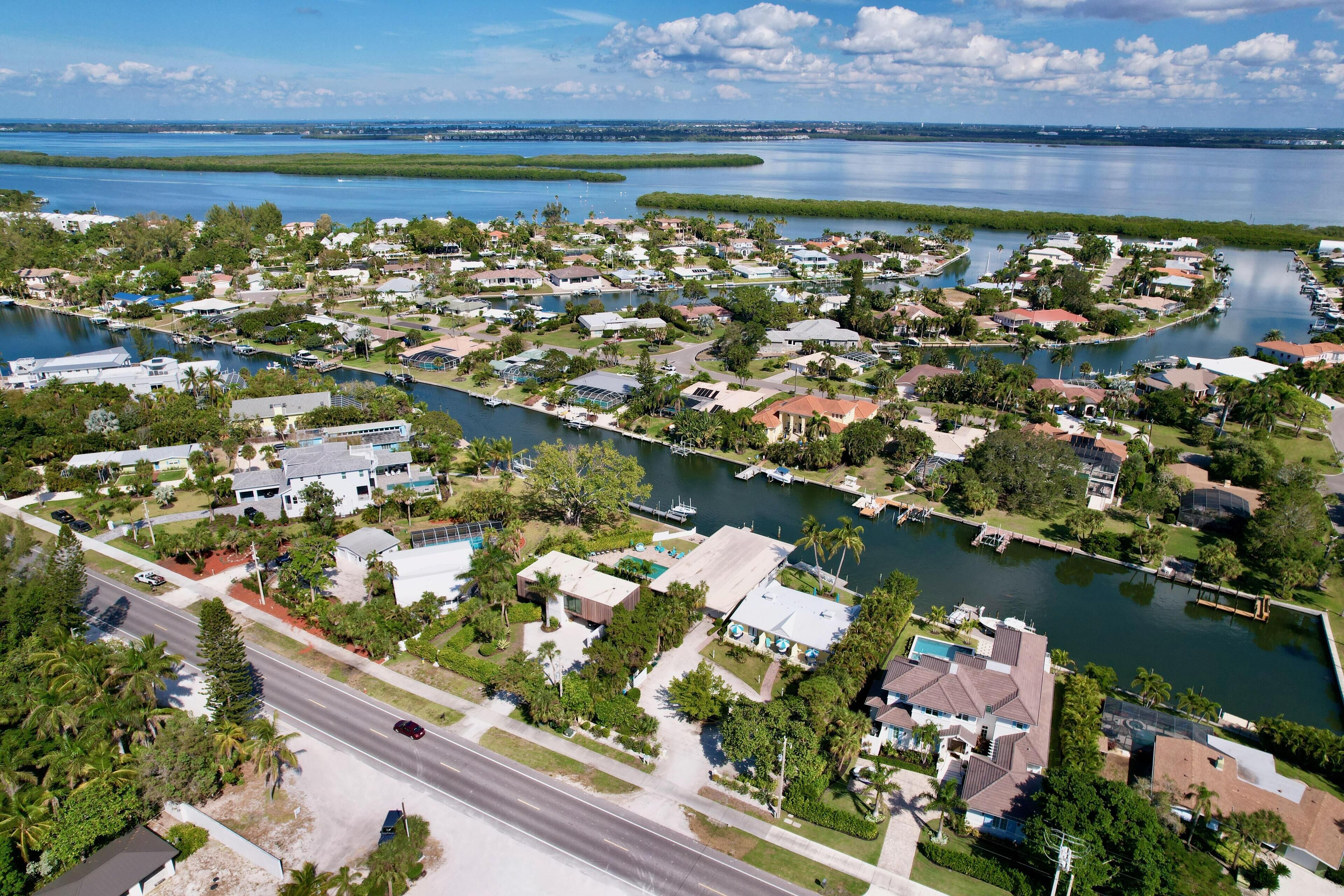 An aerial view of a residential area with houses, a road, and a body of water.