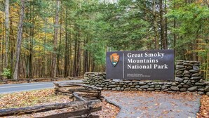 Schild für den Great Smoky Mountains Nationalpark, mit Steinmauer und Holzzaun.