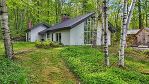 Een modern huis met een groot raam, omgeven door een bos.