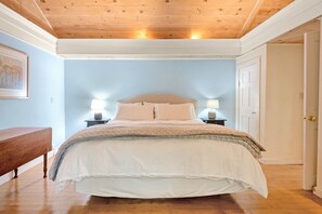 A bedroom with a wooden ceiling, a bed with white bedding, two bedside lamps, and a wooden bench. - A-Frame Chalet | Floor-to-Ceiling Windows, 1 Mi to Bromley (Peru)