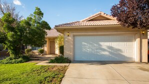 A residential house with a white garage door, a well-maintained lawn, and a clear sky. - Outstanding Northeast Heights Home Near Casino/Golf/Breweries/Hiking/Dog Park (Albuquerque)
