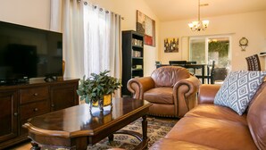 A living room with a leather sofa, a coffee table, a TV, and a bookshelf. - Outstanding Northeast Heights Home Near Casino/Golf/Breweries/Hiking/Dog Park (Albuquerque)