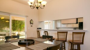 A dining area with a wooden table and chairs, a grill, and a kitchen area with cabinets and a window. - Outstanding Northeast Heights Home Near Casino/Golf/Breweries/Hiking/Dog Park (Albuquerque)