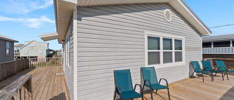 A house with a deck, two chairs, and a window.