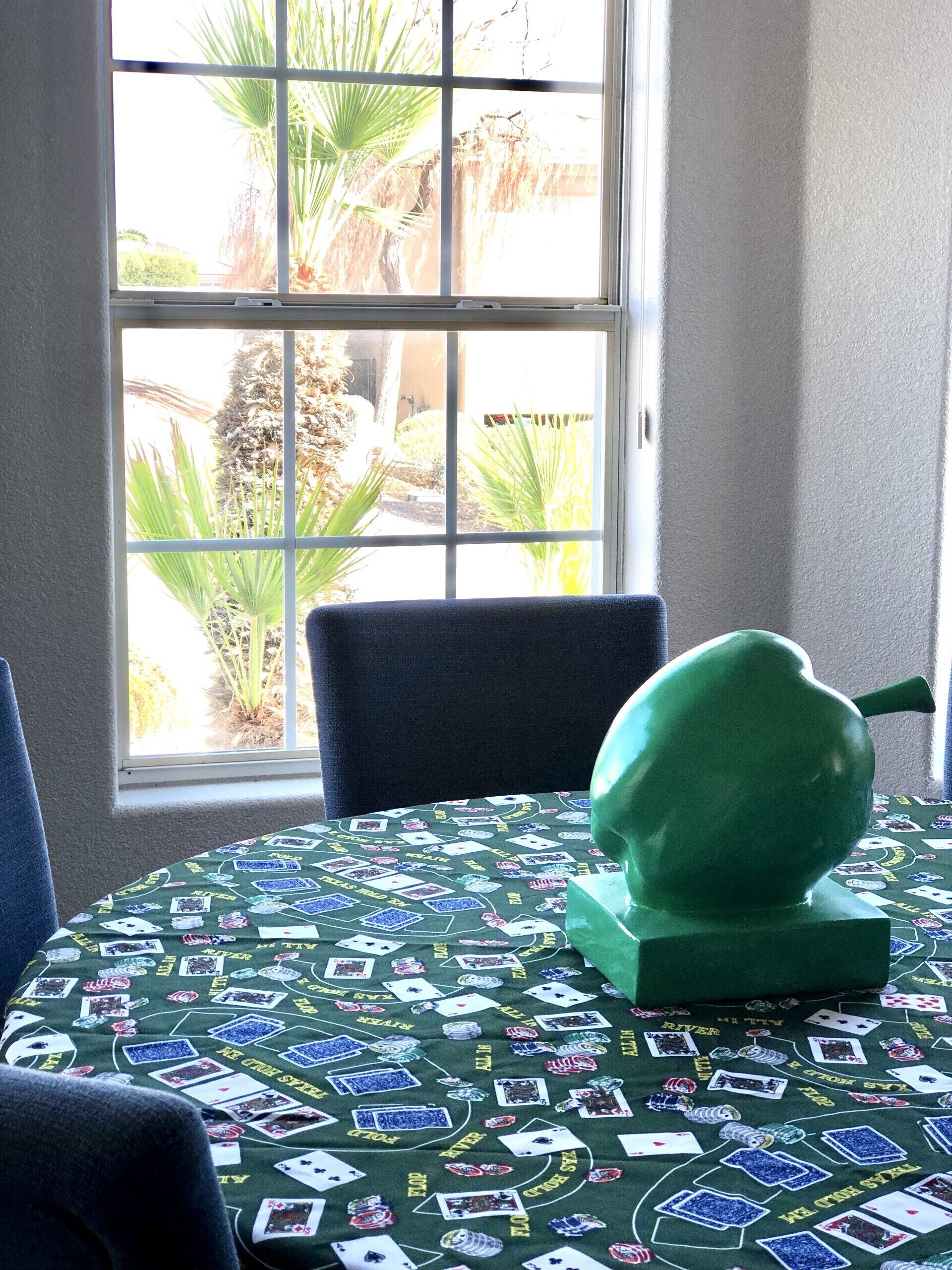 Ein Zimmer mit Fensterblick auf einen Garten, ein grüner Tisch mit Pokertisch-Tuch und ein grüner Stuhl.