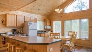 L’intérieur d’un chalet en bois comprend une cuisine, des tabourets de bar et une table à manger.