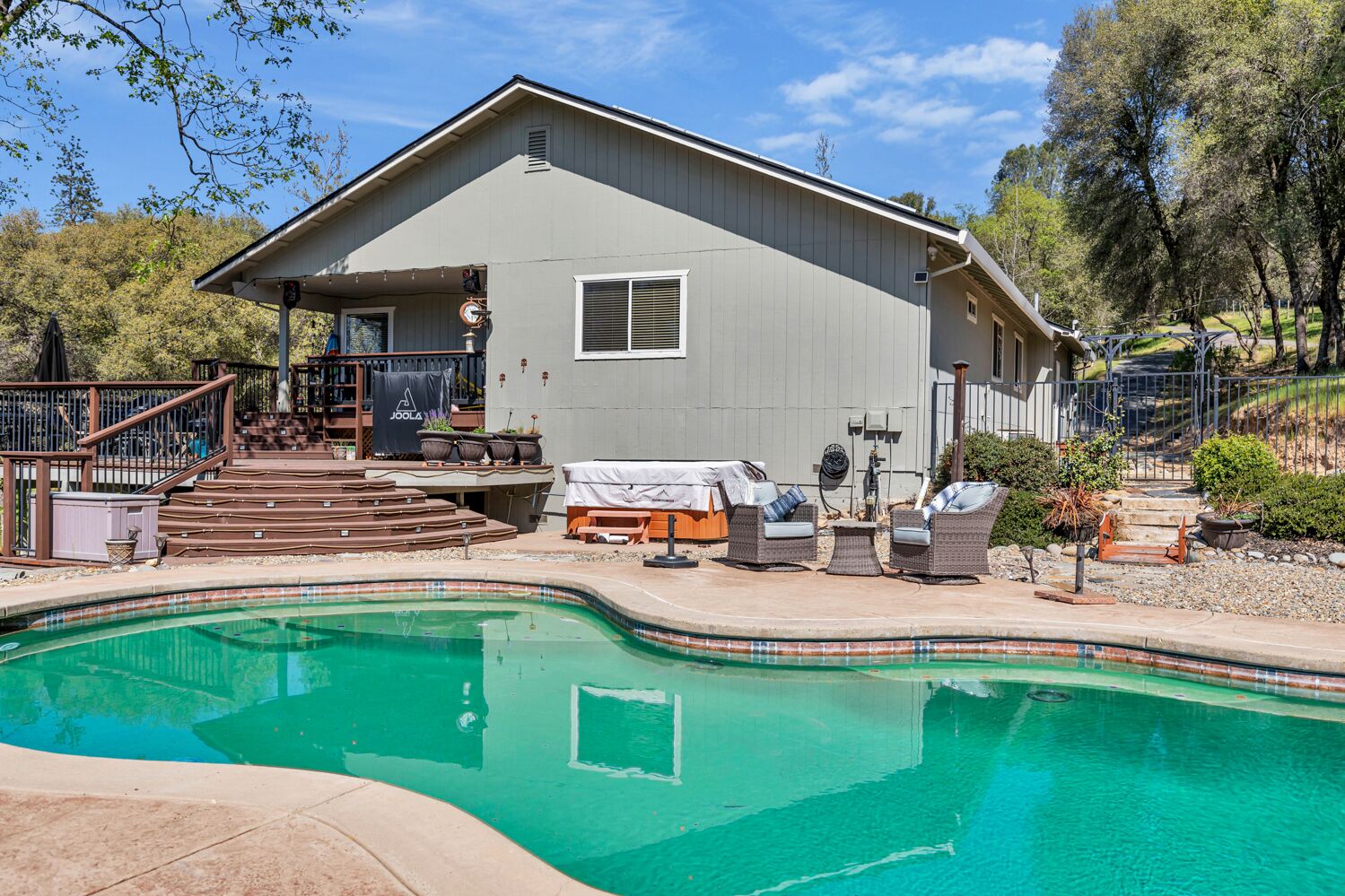 A house with a swimming pool, outdoor furniture, and a covered patio area.