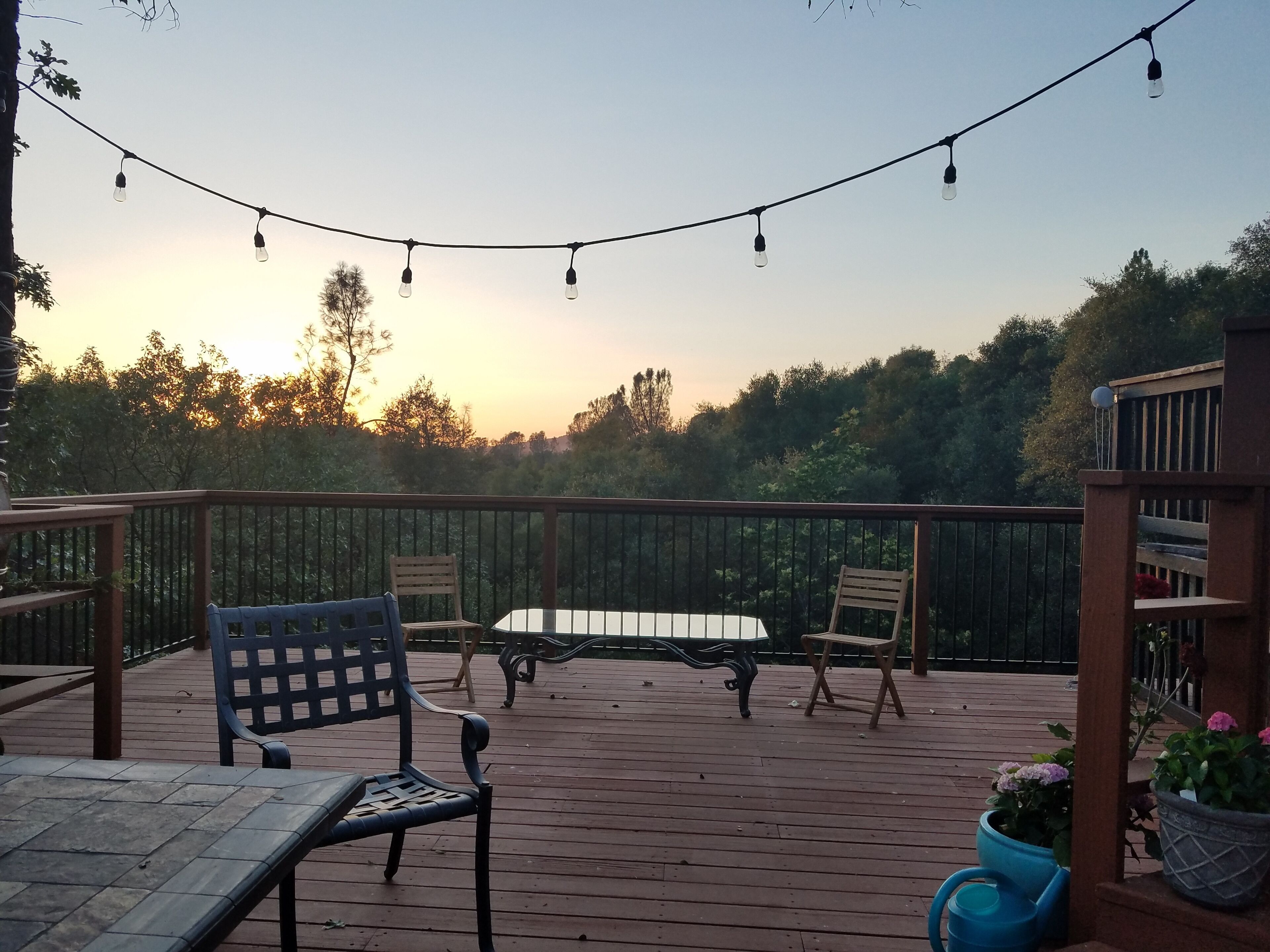 En træterrasse med et bord og stole, omgivet af gelænder og plantekasser.