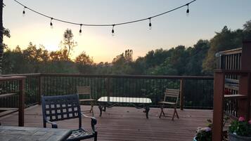 En træterrasse med et bord og stole, omgivet af gelænder og plantekasser.