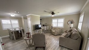 Una sala de estar con sofá, una silla, un televisor y una mesa de comedor.