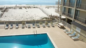 Zona de piscina con sillones reclinables, un muelle de madera y vista a la playa y al océano.