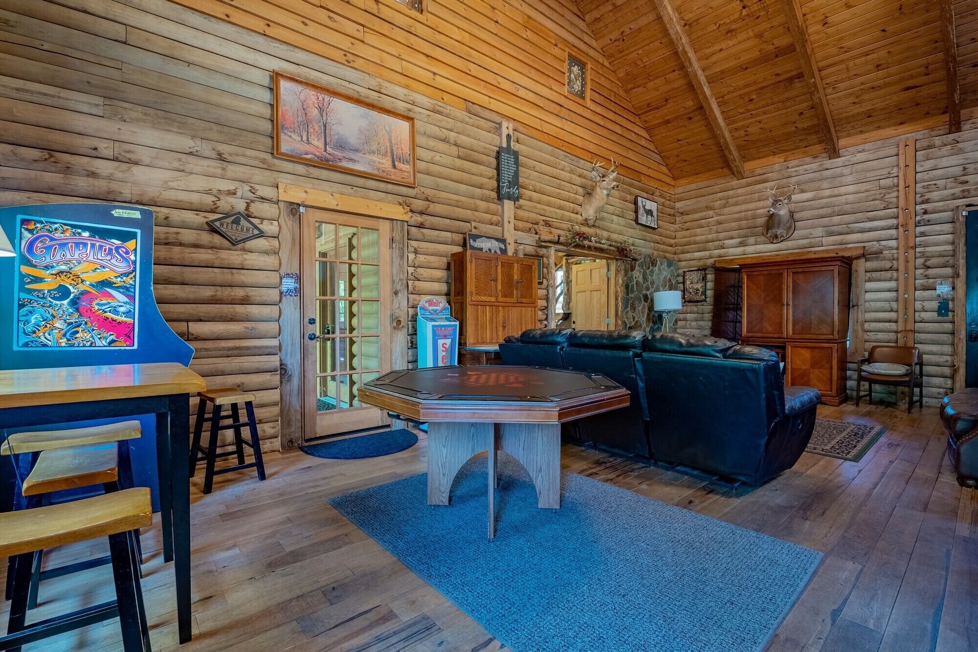 Ein Blockhaushaus-Interieur mit einem Holztisch, einer Couch, einem Schrank und einem Bild an der Wand.