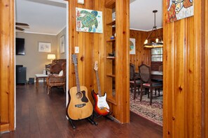 Een kamer met houten lambrisering, twee gitaren, een eettafel, stoelen en een wereldbol als kunstwerk aan de muur.
