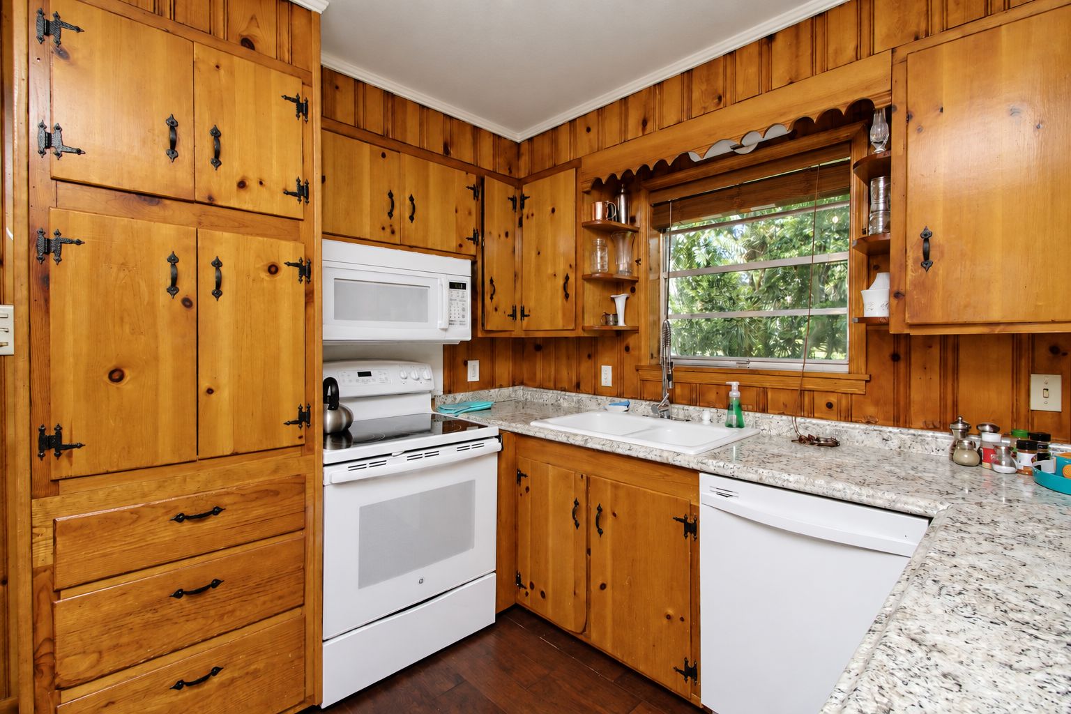 A kitchen with wooden cabinets, a white stove, a microwave, and a granite countertop.