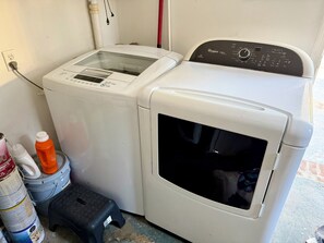 A laundry area with two washing machines, a step stool, and cleaning supplies.