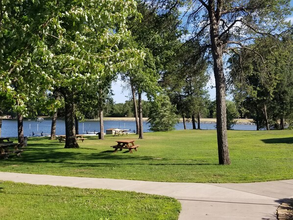 Un parque con mesas de picnic y un lago.