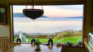 Une table à manger donnant sur un lac, un luminaire suspendu et une horloge au mur.