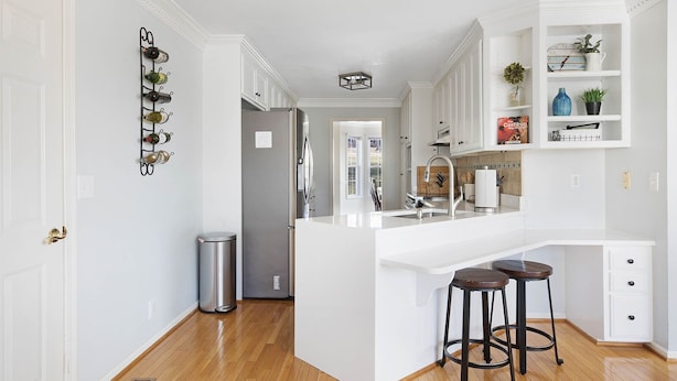 A modern kitchen with white cabinetry, a stainless steel refrigerator, and a built-in island with stools. - Lakefront, Swimming pool family home minutes from downtown Nashville (Hendersonville)