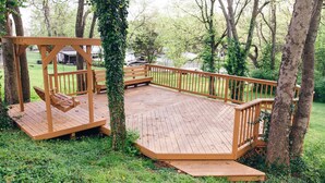 A wooden deck with a swing set and benches, surrounded by trees and a grassy area. - Lakefront, Swimming pool family home minutes from downtown Nashville (Hendersonville)
