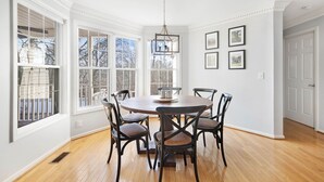 A dining room with a round table, six chairs, and large windows. - Lakefront, Swimming pool family home minutes from downtown Nashville (Hendersonville)