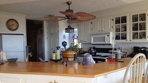 A kitchen with white cabinets, a wooden countertop, a ceiling fan, a microwave, and a clock on the wall. -  Cottage on a Private Island in the York River (Gloucester Point)